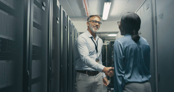 Shot of a man and woman shaking hands while working in a server room