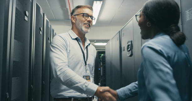 istock Shot of a man and woman shaking hands while working in a server room 1340944452