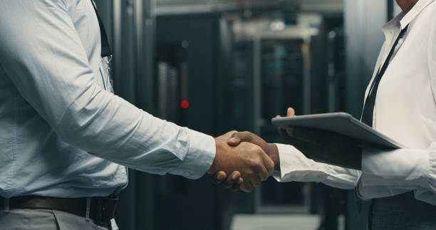 istock Shot of a man and woman shaking hands while working in a server room 1340944459