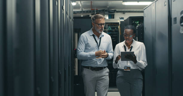 Shot of a man and woman using a digital tablet while working in a data centre stock photo