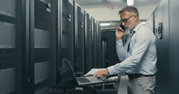 istock Shot of a mature man using a laptop and smartphone while working in a data centre 1340946360