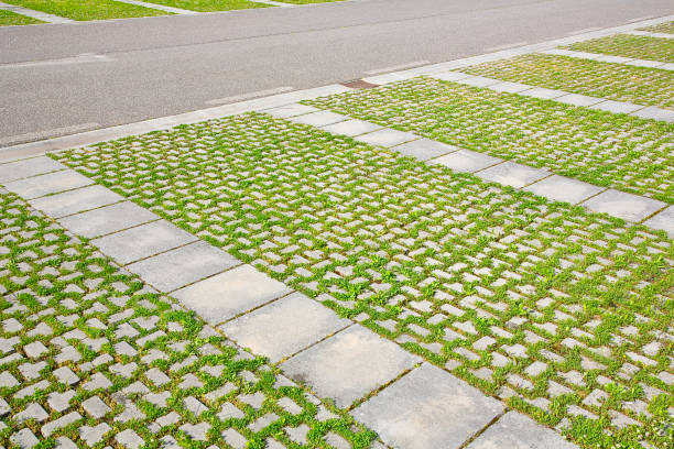 blocos de piso de concreto cinza montados em um substrato de areia com grama - tipo de piso permeável à água da chuva, conforme exigido pelas leis de construção usadas para calçadas e áreas de estacionamento - concrete driveway construction site construction - fotografias e filmes do acervo