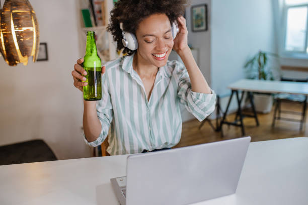 woman is attending online party and drinking beer at home - after work beautiful people beer beer bottle imagens e fotografias de stock