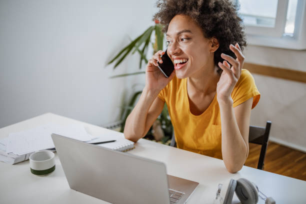 istock Woman is using laptop and talking on the phone 1340948616