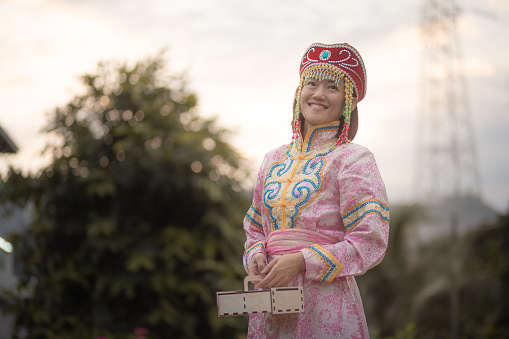 Asia Chinese mature woman with traditional clothes holding moon cake  box  enjoy moon cake festival at backyard.