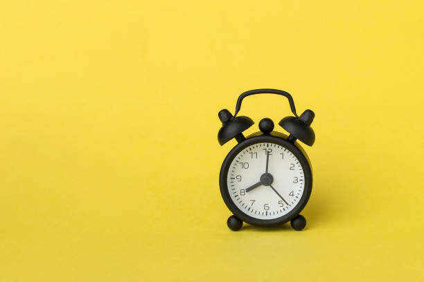 istock A small alarm clock on yellow background, 8 o'clock 1340953645
