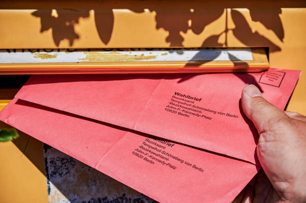 An election letter being thrown into the mail slot of a mailbox. Berlin, Germany - September 09, 2021: An election letter being thrown into the mail slot of a mailbox for the federal election in Germany. german federal elections photos stock pictures, royalty-free photos & images