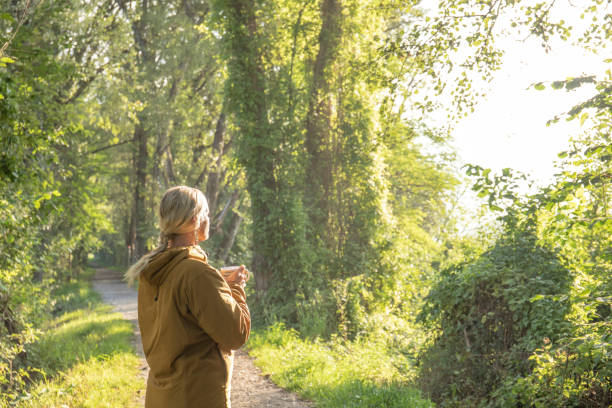 la donna si ferma sul sentiero boscoso prima dell'escursione mattutina - footpath field nature contemplation foto e immagini stock