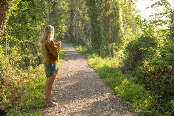She enjoys coffee, and looks out through lush forest