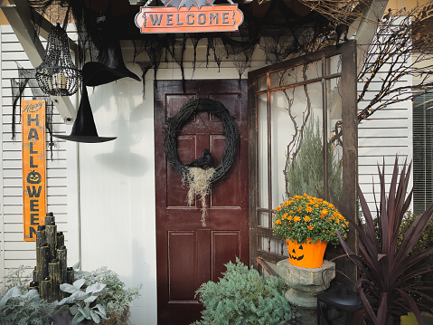 Spooky front entrance Halloween decor. Welcome sign, wreath on door