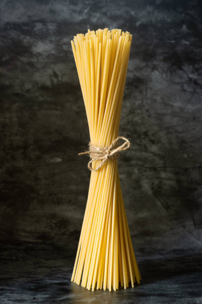 istock raw spaghetti stands upright on a dark background, tied with a rope 1340957037