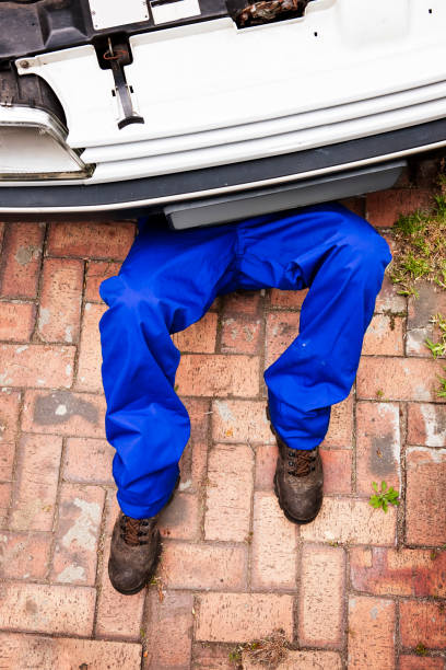 Mechanic Auto mechanic's legs protrude from under a car. Camera: Canon EOS 1Ds Mark III. mechanic working under car stock pictures, royalty-free photos & images