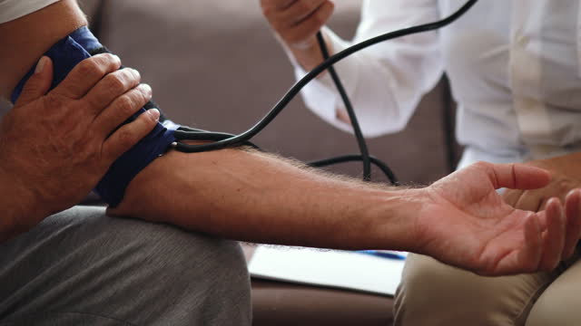 Female doctor checking patients blood pressure during home visit