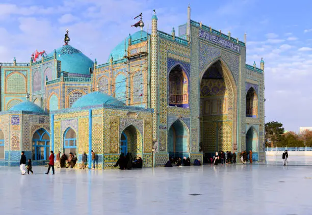 Mazar-i-Sharif, Balkh province, Afghanistan: Shrine of Ali (Hazrat Ali Mazar) aka Blue Mosque or Rawza - central element of Mazar's main square, Rawza square - known as the burial place of Ali ibn Abi Talib, cousin of Mohammed. He was the first male follower of Muhammad and married his daughter Fatima. Ali was the fourth Rightly Guided caliph and is regarded as the rightful immediate successor to Muhammad and the first Imam by Shia Muslims. It is controversial among historians whether Ali is actually buried there. The Imam Ali mosque in Najaf in Iraq is also considered the burial place of Ali ibn Abi Talib. Covered in intricate Persian Qashani tile work with calligraphy and Islamic patterns. Numerous incidental people in the image, none prominent.