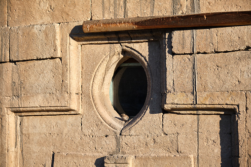 A wall and round style windows and small birds of sparrow on wall made of limestone