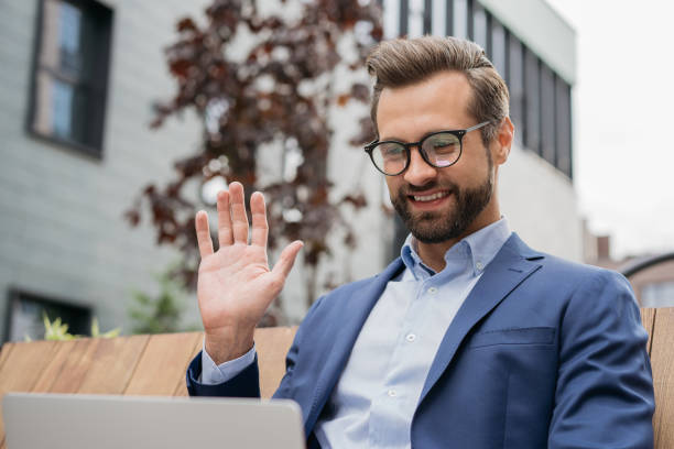 istock Handsome smiling businessman using laptop computer having video call, greeting. Happy bearded man influencer in stylish eyeglasses communication online. Video conference concept 1340973272