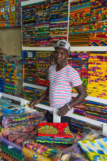 Banjul, The Gambia - may 09, 2017: Young employee in a fabric store in front of the Albert Market