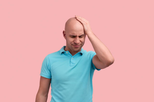 istock Facepalming. Upset bald homosexual man with bristle keeps hand on forehead, feels stressed, regrets wrong doing, gay friendly, wears blue polo shirt, poses over pink background. 1340977041