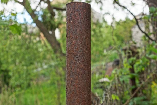 part one brown rusty iron pipe on the street against the background of green vegetation