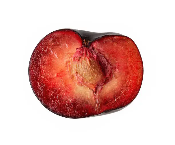 Half of ugly organic misshapen black plum with stone isolated on white background. Red pulp plum. Trendy ugly imperfect fruits concept. Misfit or deformed harvest design element. High quality macro. Close-up.