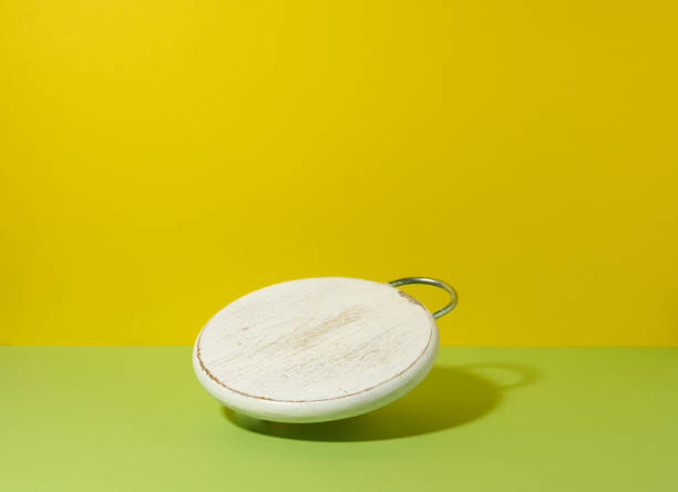 istock round empty white wooden kitchen board on yellow green background, utensils levitate 1340978840