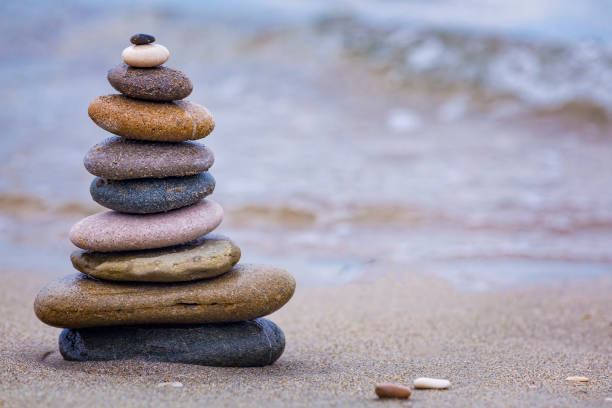 istock Rock balancing or stone stacking, rock stone or sea pebbles pile or pyramid on sand symbolizing zen, harmony, balance. Ocean water and sunset on background. Relaxation concept. Empty space for text. 1340980880