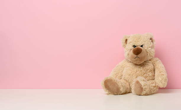istock brown teddy bear with a sad face sits on a white table, pink background 1340981278