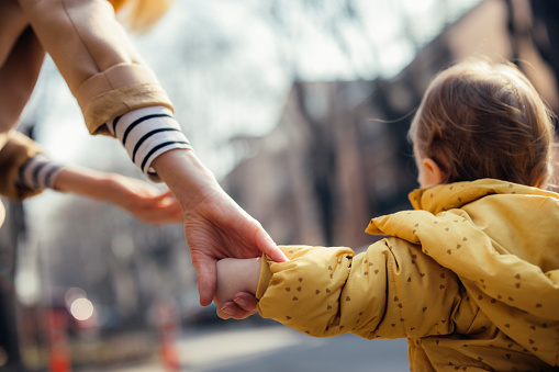 Close up photo of a  mother holding daughter hand and enjoying a walk outside