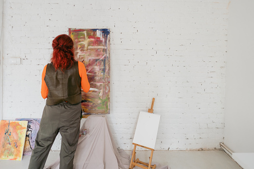 Photo of a mature woman painting on canvas at home