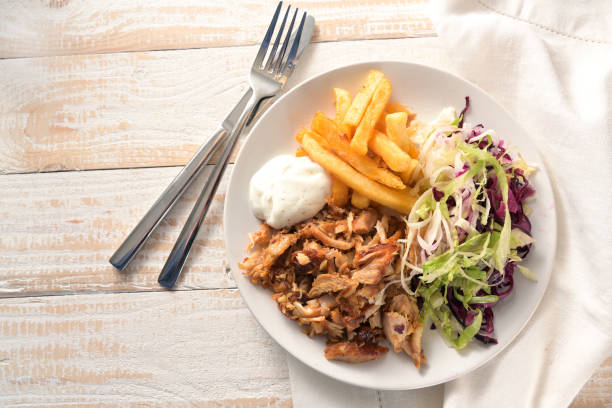 doner kebab carne de pollo con papas fritas, ensalada y salsa tzatziki, plato de comida rápida en una mesa de madera, espacio de copia, vista de ángulo alto desde arriba, enfoque seleccionado - rotisserie chicken meat dinner fotografías e imágenes de stock