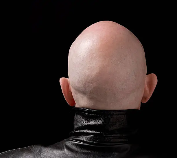 Skinhead in a leather jacket. Illustrate subcultures, racism, etc. Pure black background.