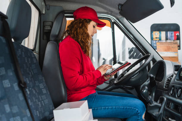 istock Female delivery driver tracking packages on a tablet in the van 1340995142
