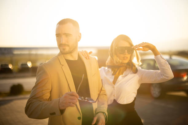 Two well dressed fashion models standing outdoors on sunny day