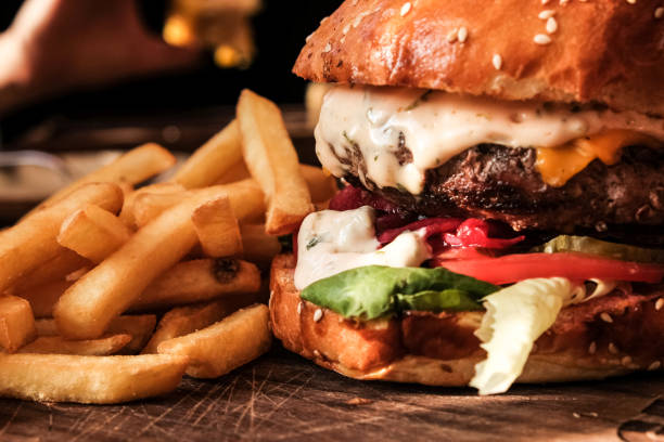 close-up of tasty hamburger with beef ground meat served with french fries on a wooden tray - bacon cheeseburger imagens e fotografias de stock