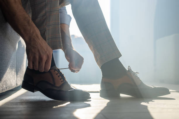 istock Man sitting and tying shoelaces, close up 1340999503