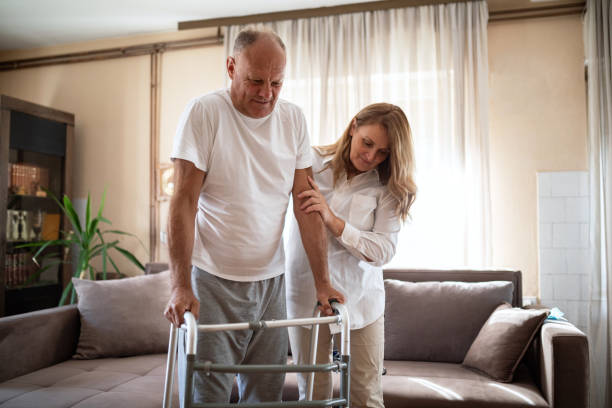 istock Wife helping her injured husband to walk using walking frame at home 1341001598