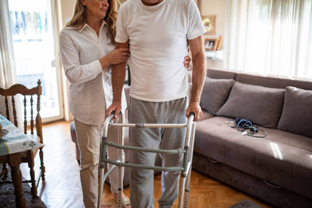 istock Wife helping her injured husband to walk using walking frame at home 1341001606