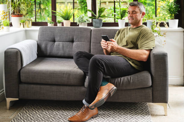 istock Shot of a mature man using a smartphone on the sofa at home 1341017043