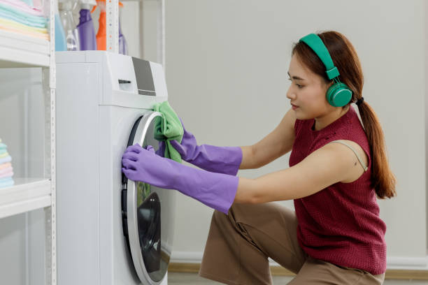 femme au foyer heureuse nettoyant lave-linge machine à laver à la maison et écoutant de la musique avec des écouteurs bluetooth wifi internet - all laundry detergent audio photos et images de collection