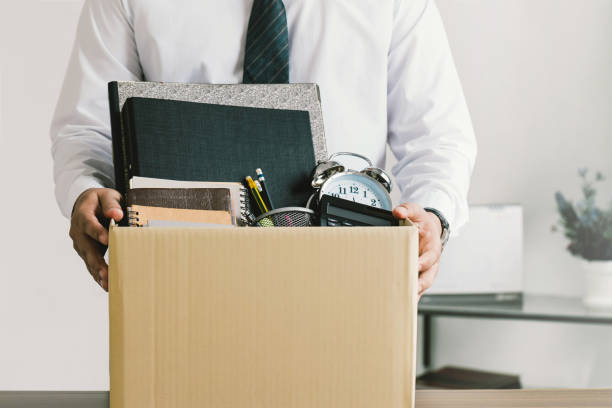 démission. des hommes d’affaires tenant des boîtes pour leurs effets personnels et des lettres de démission. quitter un emploi,le grand démissionner. la grande résignation. - rejet photos et images de collection