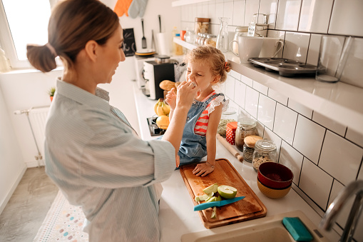 Mother and daughter spending time in kitchen, eating