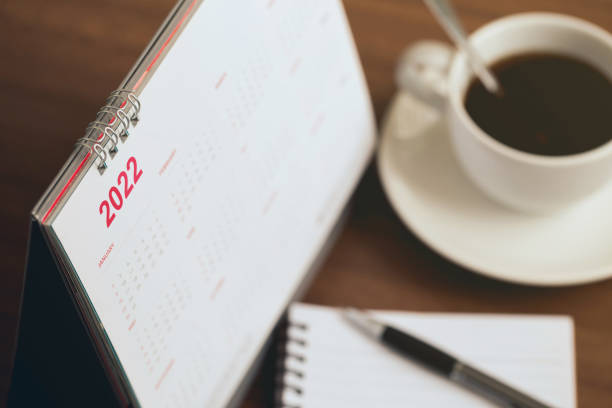 Happy new year 2022 concept.Close up Calendar 2022 schedule with cup of coffee and blank note for to do list on wooden desk.Starting the new year and planning for the future stock photo