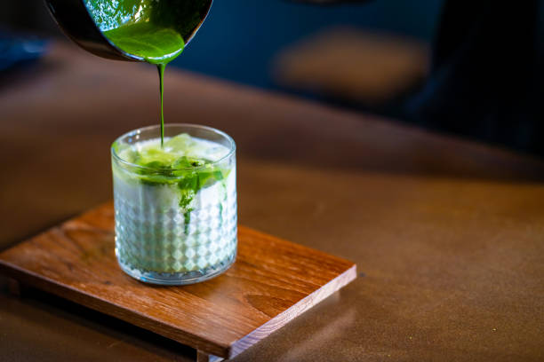 Asian woman barista making iced matcha green tea latte serving to customer at cafe Asian woman barista making matcha green tea with fresh milk in the glass. Female coffee shop waitress serving iced matcha latte to customer on counter at cafe. Small business coffee shop owner concept restaurant labor union stock pictures, royalty-free photos & images
