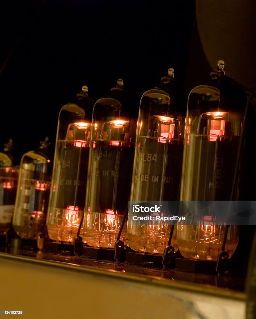 Vacuum tubes glowing Quartet of EL84 vacuum tubes (aka valves) glowing in the chassis of a guitar amplifier. Two 12AX7 preamp tubes can also be seen at the far end of the row. Amplifier Stock Photo