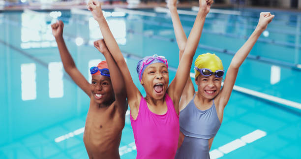 porträt einer gruppe kleiner kinder, die während einer schwimmstunde in einem hallenbad jubeln - schwimmen fotos stock-fotos und bilder