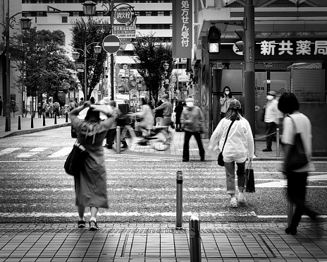 Yokosuka, Kanagawa Prefecture, Japan - September 14, 2021: Masked pedestrians passing through a crosswalk at a busy downtown intersection on Blue Street.