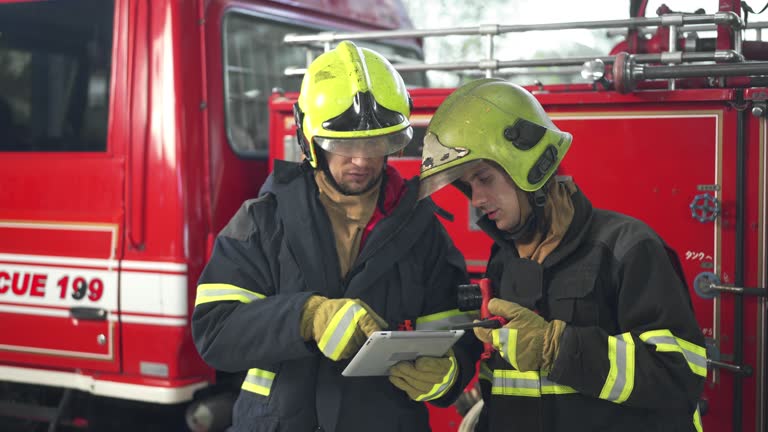 Two Male Firefighters Using Digital Tablet Working In Fire Station