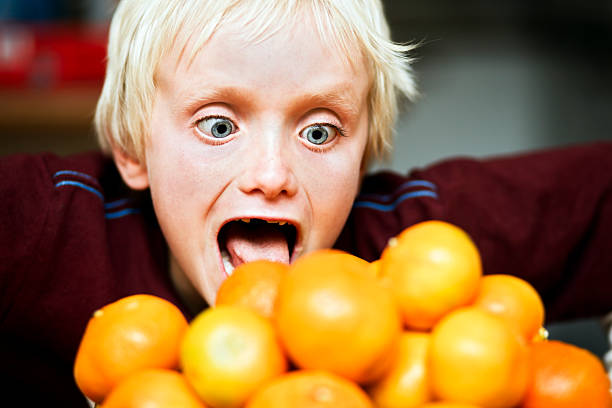 탐욕! 소년만 런지 더미 에서 맛있는 감귤류 과일. - greed child eating mandarin orange 뉴스 사진 이미지