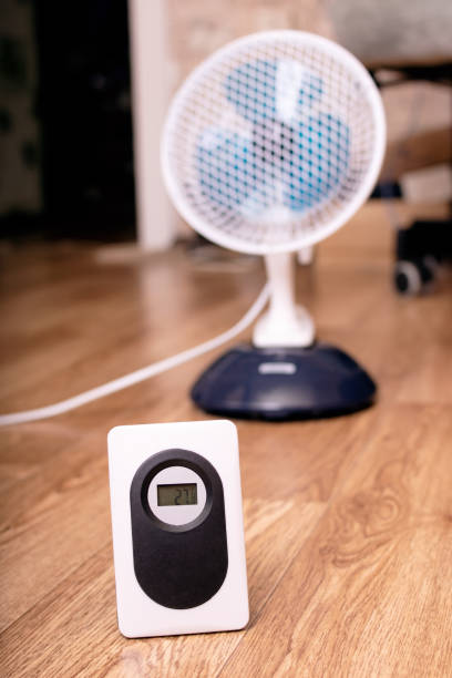 istock Small fan and room electronic thermometer closeup 1341041339