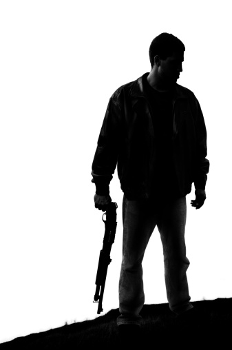 A man wearing a leather jacket and wielding a shotgun. High contrast and slight grain gives this image a dramatic feel.